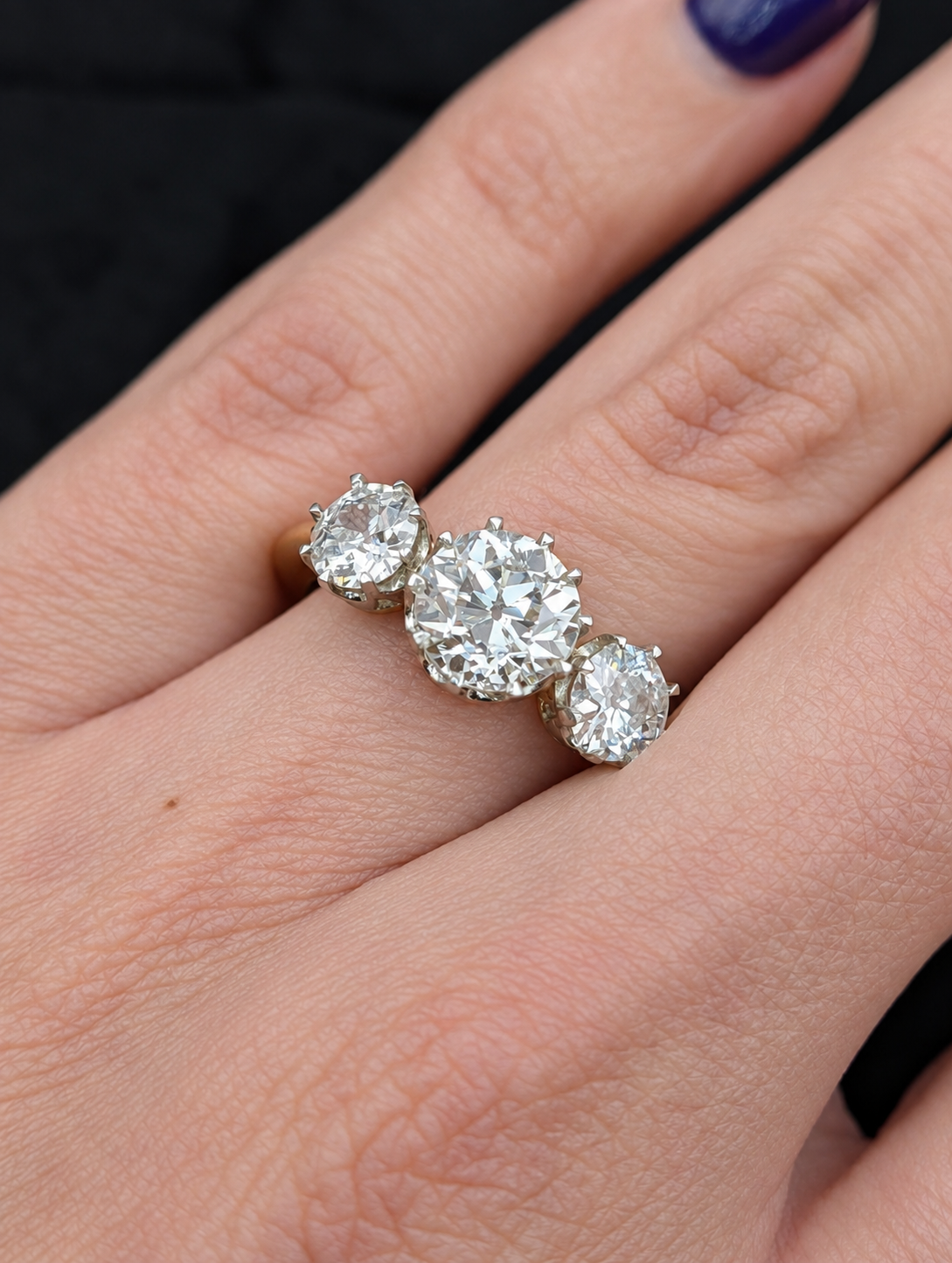 Close-up of the 3.05 carat three-stone old European cut diamond ring worn on the hand