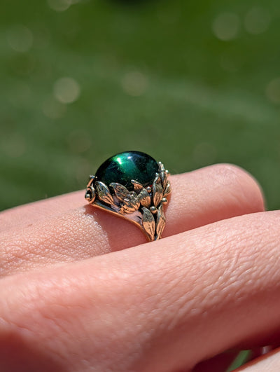 Side view of domed green tourmaline and sculpted gold leaves