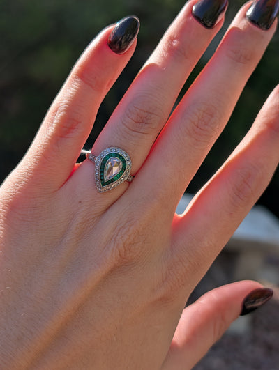 Pear rose-cut diamond and emerald platinum ring worn on the hand