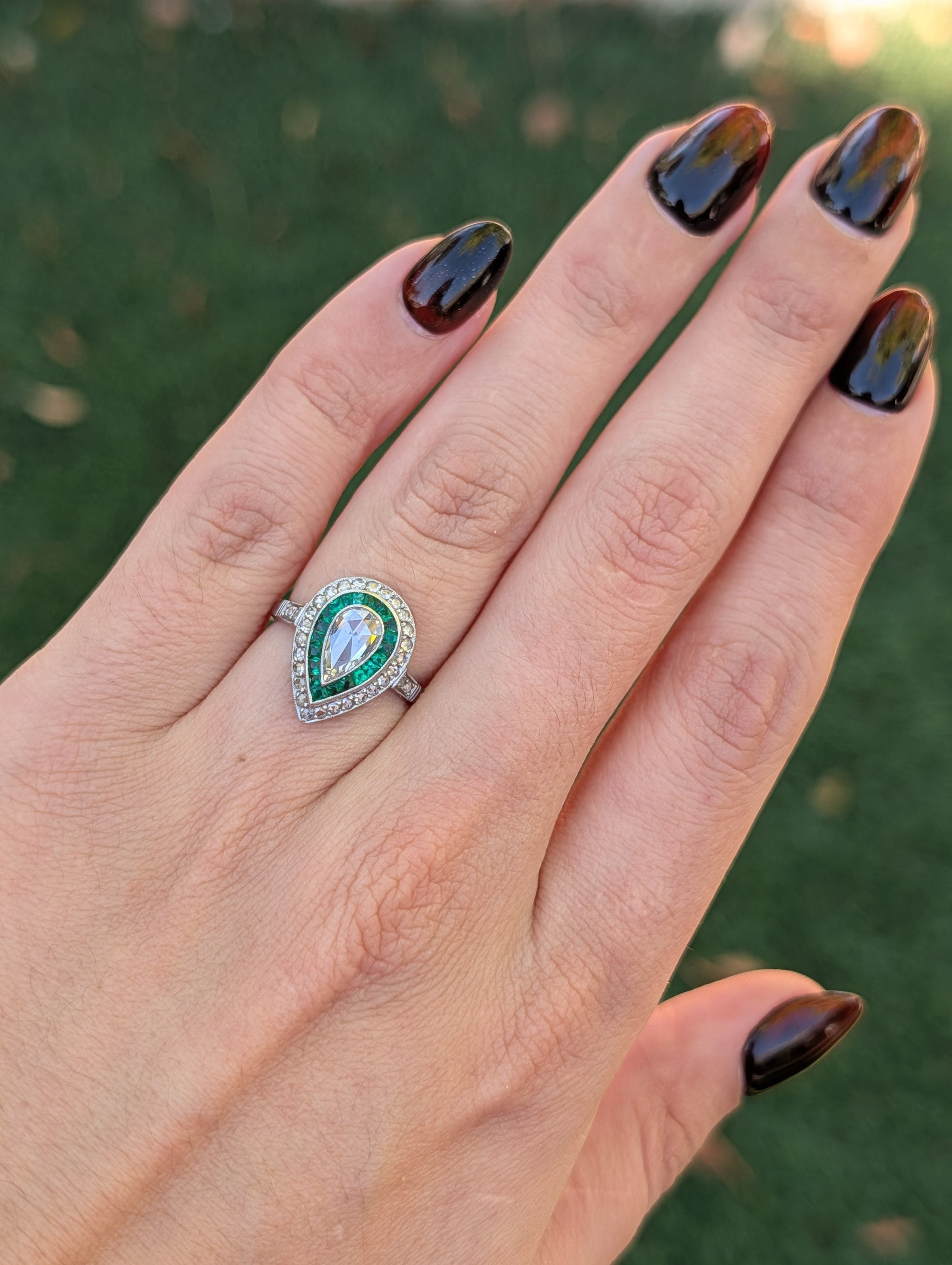 Pear rose-cut diamond and emerald platinum ring worn on the hand