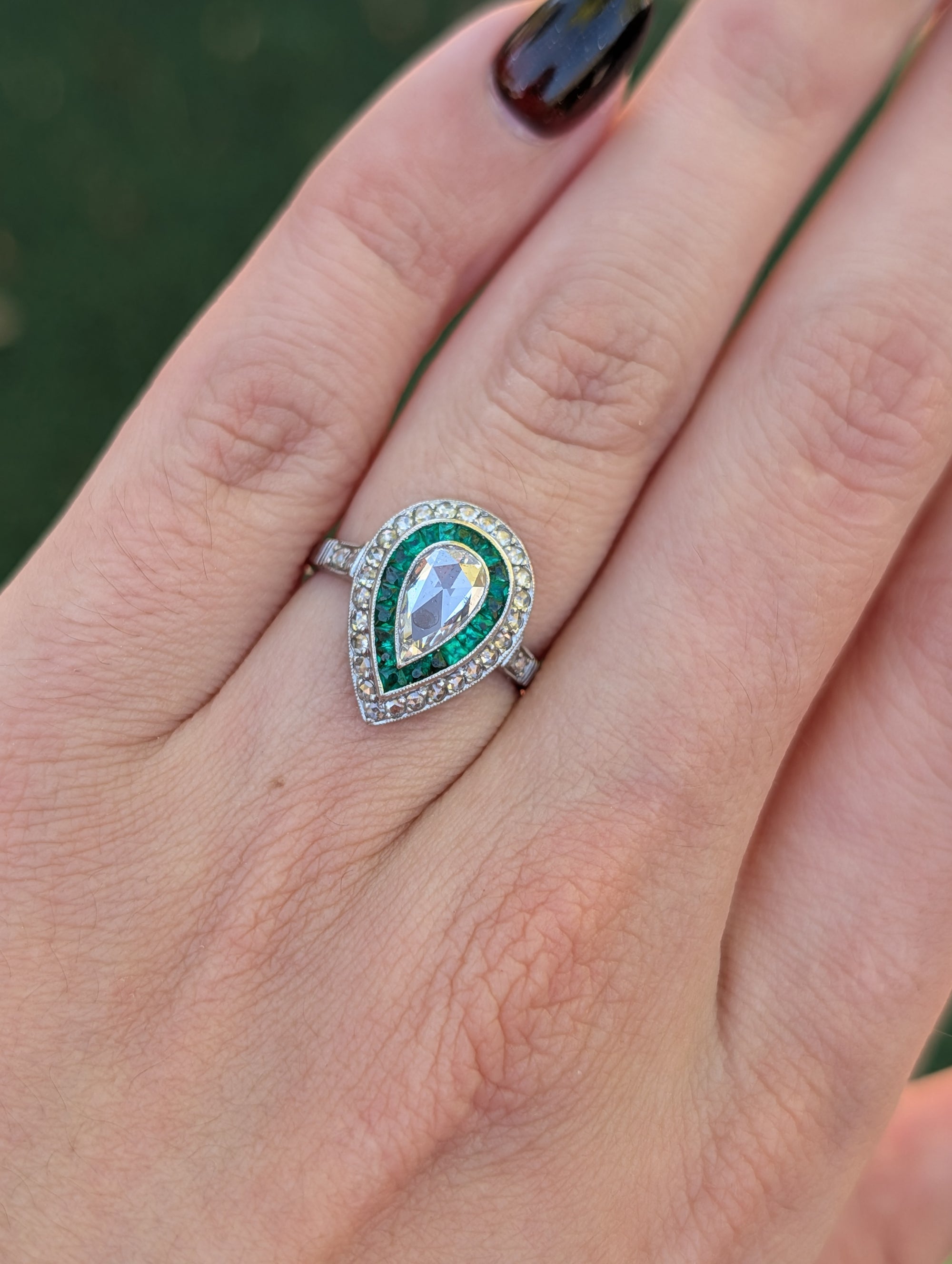Pear rose-cut diamond and emerald platinum ring worn on the hand