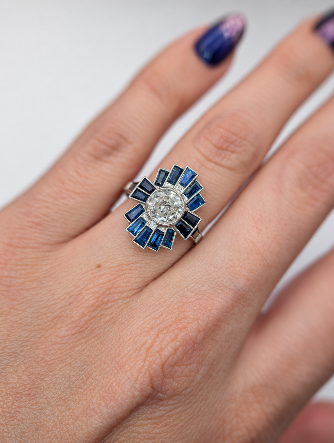 Art Deco style platinum diamond and natural blue sapphire ring worn on hand