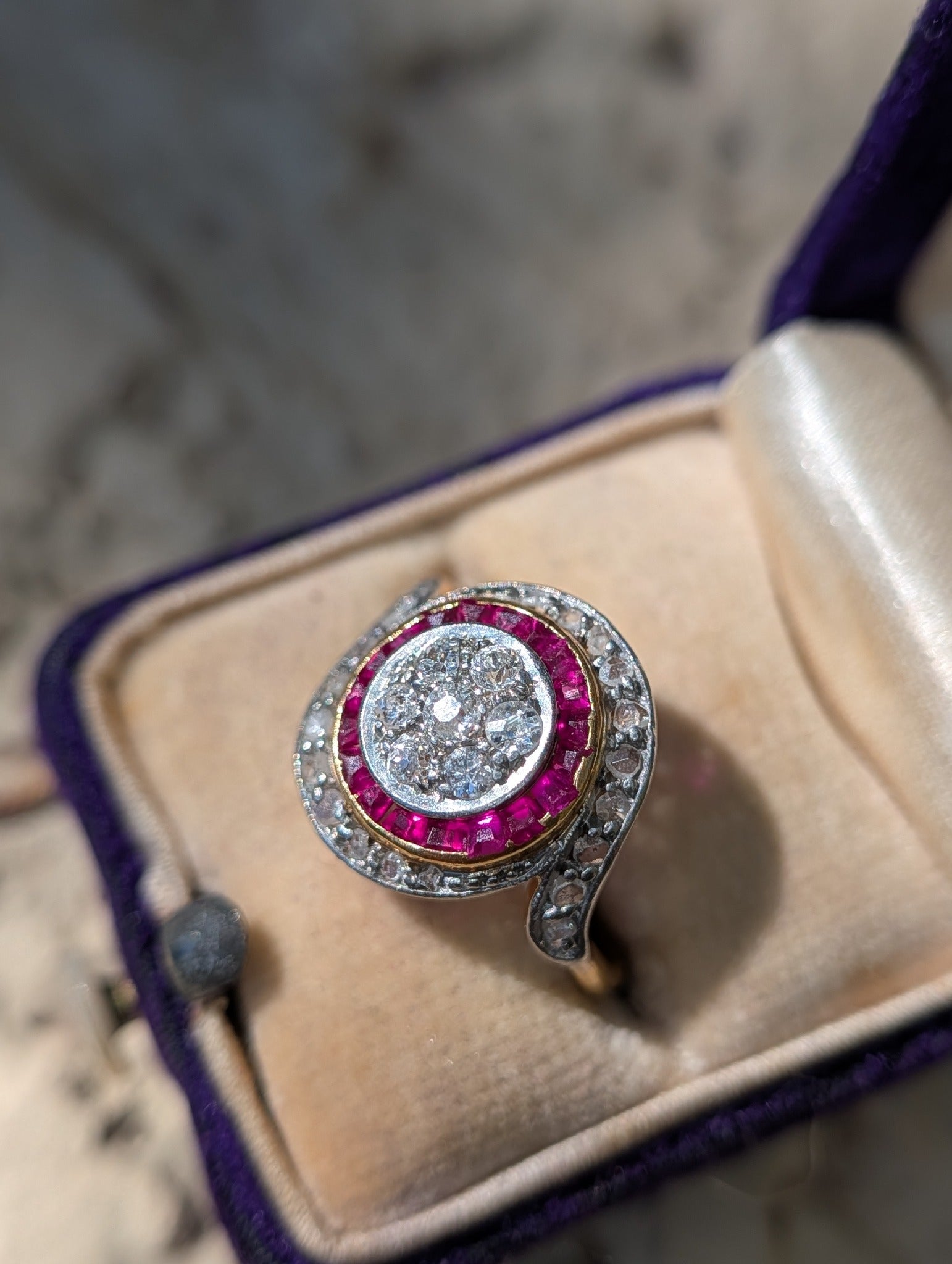 Close view of diamond cluster and synthetic ruby border in 18k gold and platinum