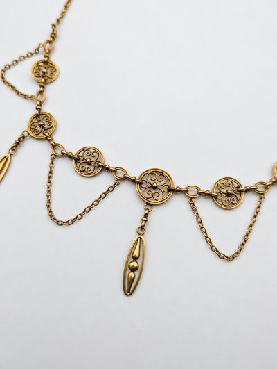 Close-up of the French 18K gold festoon necklace scrollwork and suspended drop